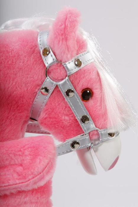 Różowy koń na biegunach z kokardkami w srebrnej uprzęży