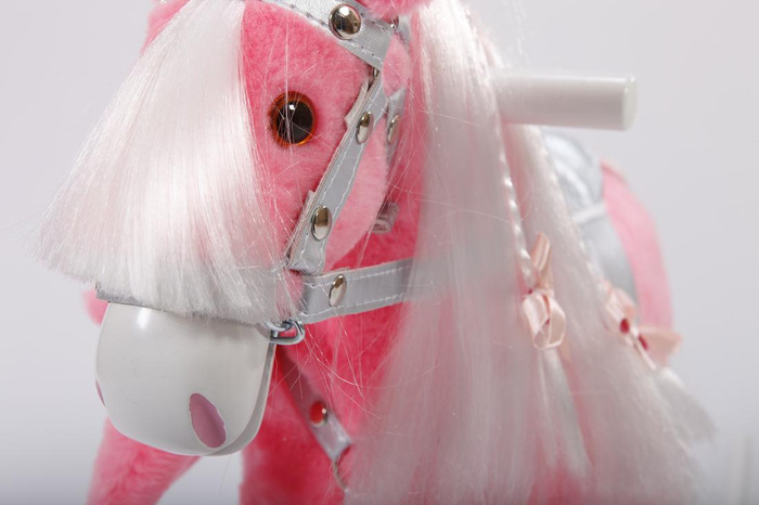 Różowy koń na biegunach z kokardkami w srebrnej uprzęży