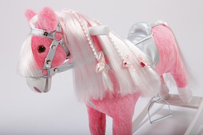 Różowy koń na biegunach z kokardkami w srebrnej uprzęży